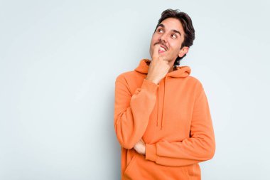 Mavi arka planda izole olmuş genç İspanyol bir adam rahatlamış bir şeyin fotokopi odasına baktığını düşünüyor..