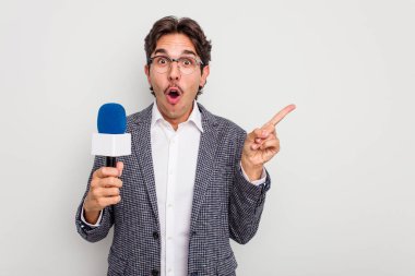 Beyaz arka planda izole edilmiş genç İspanyol TV sunucusu yan tarafı işaret ediyor.