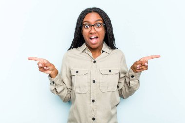 Mavi arka planda saçı olan genç Afrikalı Amerikalı kadın farklı kopya alanlarını gösteriyor, birini seçiyor, parmaklarıyla gösteriyor..