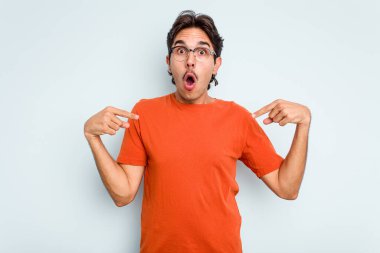 Genç İspanyol bir adam mavi arka planda izole edilmiş. Parmakları aşağıda, olumlu hisler içinde..