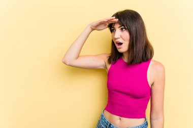 Sarı arka planda izole edilmiş, elini alnına koyan genç, beyaz bir kadın..