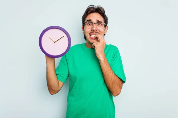 Young Hispanic Man Holding Clock Isolated White Background Biting Fingernails — Stock Photo, Image