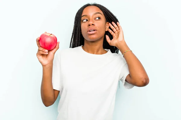 Ung Afroamerikansk Kvinna Håller Ett Äpple Isolerat Blå Bakgrund Försöker — Stockfoto