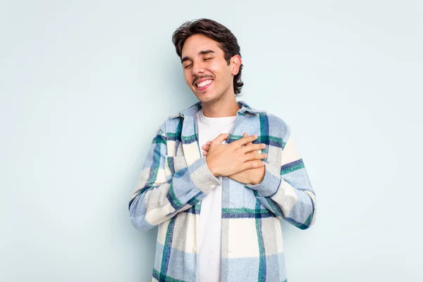青い背景の上に孤立した若いヒスパニック系の男は 心に手を取り合って笑って 幸福の概念 — ストック写真