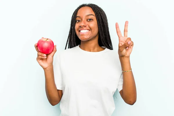 Ung Afroamerikansk Kvinna Håller Ett Äpple Isolerat Blå Bakgrund Visar — Stockfoto