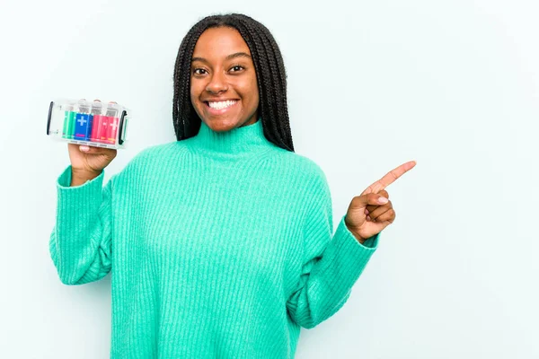 青い背景にバッテリーボックスを持っている若いアフリカ系アメリカ人女性は笑顔と脇を指して 空白のスペースで何かを示しています — ストック写真