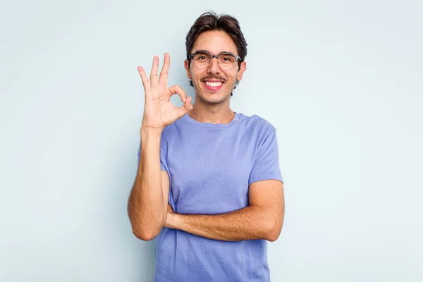 Mladý Hispánec Izolovaný Modrém Pozadí Mrkne Okem Drží Ruce Dobré — Stock fotografie