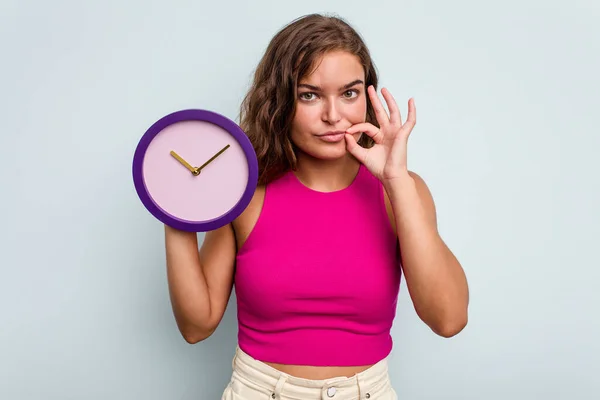 Mujer Caucásica Joven Sosteniendo Reloj Aislado Sobre Fondo Azul Con —  Fotos de Stock