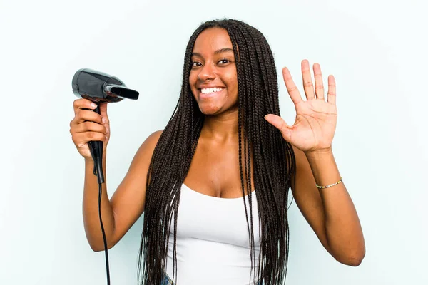 Молодая Афроамериканка Держащая Фен Синем Фоне Весело Улыбаясь Показывает Номер — стоковое фото