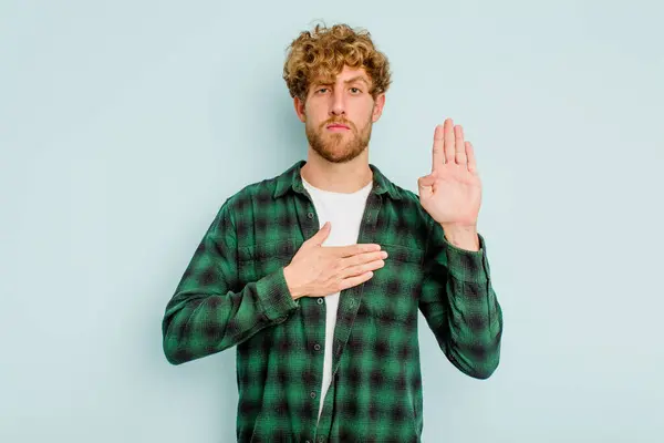 Young Caucasian Man Isolated Blue Background Taking Oath Putting Hand — Stock Photo, Image