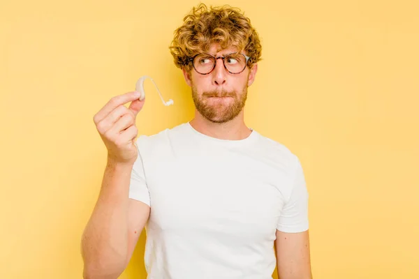 Junger Kaukasier Mit Hörgerät Auf Gelbem Hintergrund Verwirrt Fühlt Sich — Stockfoto