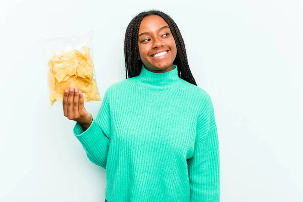 Ung Afroamerikansk Kvinna Håller Potatischips Isolerad Blå Bakgrund Ser Sidan — Stockfoto