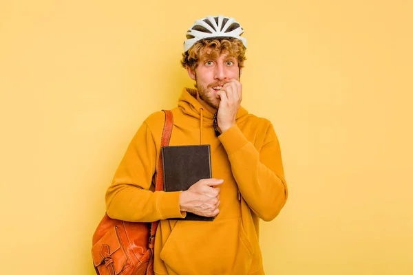 年轻的学生骑着头盔自行车 被黄色的背景隔离 咬着指甲 神经紧张 非常焦虑 — 图库照片