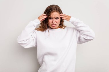 Kafkasyalı genç bir kadın mavi arka planda izole edilmiş, başı ağrıyor, yüzüne dokunuyor..