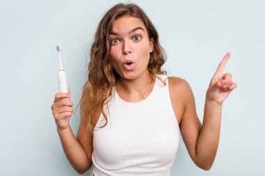 Elinde elektrikli diş fırçası olan beyaz bir kadın mavi arka planı izole etti. Harika bir fikri var, yaratıcılık kavramı..