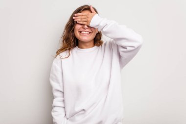 Mavi arka planda soyutlanmış beyaz bir kadın elleriyle gözlerini kapatıyor, gülümseyerek bir sürpriz bekliyor..