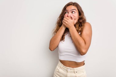 Kafkasyalı genç bir kadın mavi arka planda izole edilmiş düşünceli bir şekilde ağzıyla ağzını kapatan bir fotokopi odasına bakıyor..