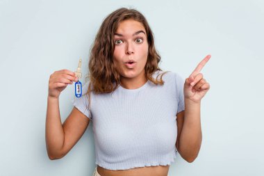 Young caucasian woman holding home keys isolated on blue background having some great idea, concept of creativity.