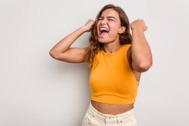 Genç beyaz kadın mavi arka planda izole edilmiş zafer sonrası yumruğunu kaldırıyor, kazanan konsept..