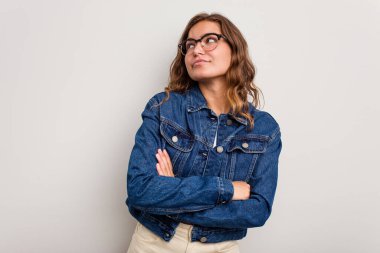 Mavi arka planda izole edilmiş genç beyaz kadın hedeflerine ve amaçlarına ulaşma hayali kuruyor.