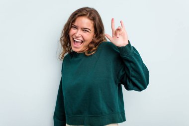 Mavi arka planda izole edilmiş genç beyaz kadın boynuzlarını devrim konsepti olarak gösteriyor..