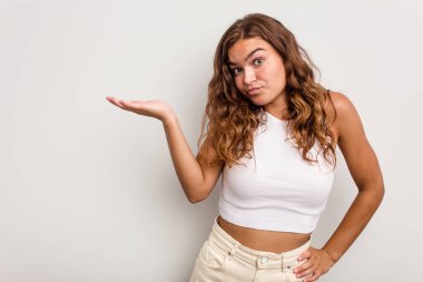 Mavi arka planda izole edilmiş genç beyaz kadın bir avuç içinde fotokopi alanı ve belinde bir el daha gösteriyor..