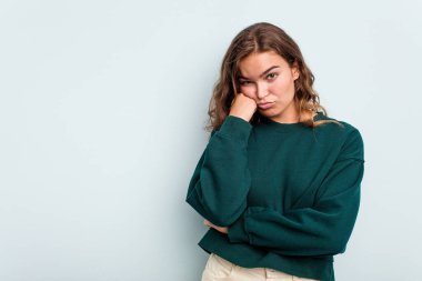 Mavi arka planda izole edilmiş, üzgün ve dalgın hisseden, kopyalama alanına bakan beyaz bir kadın..