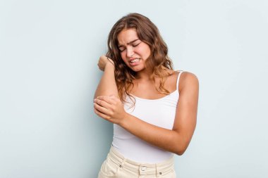 Beyaz bir kadın mavi arka planda izole edilmiş dirsek masajı yapıyor, kötü bir hareketin ardından acı çekiyor..