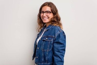 Kafkasyalı genç bir kadın mavi arka planda izole edilmiş. Kendine güvenen, ellerini kalçasında tutan..