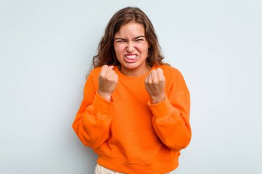 Mavi arka planda izole edilmiş genç beyaz kadın gergin elleriyle çığlık atıyor..