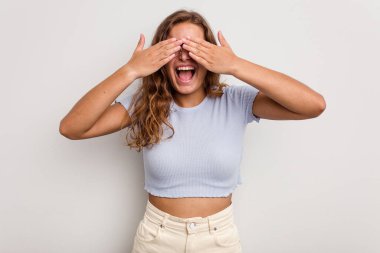 Mavi arka planda soyutlanmış beyaz bir kadın elleriyle gözlerini kapatıyor, gülümseyerek bir sürpriz bekliyor..