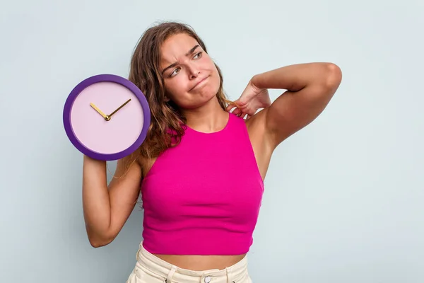 Mujer Caucásica Joven Sosteniendo Reloj Aislado Sobre Fondo Azul Tocando —  Fotos de Stock