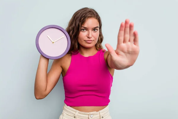 Mujer Caucásica Joven Sosteniendo Reloj Aislado Sobre Fondo Azul Pie —  Fotos de Stock