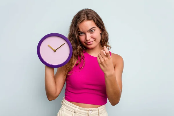 Молода Біла Жінка Тримає Годинник Ізольовано Синьому Фоні Вказуючи Пальцем — стокове фото