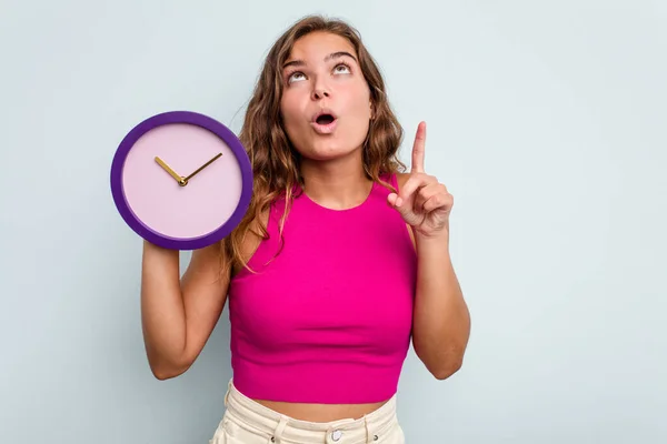 Joven Mujer Caucásica Sosteniendo Reloj Aislado Sobre Fondo Azul Apuntando — Foto de Stock