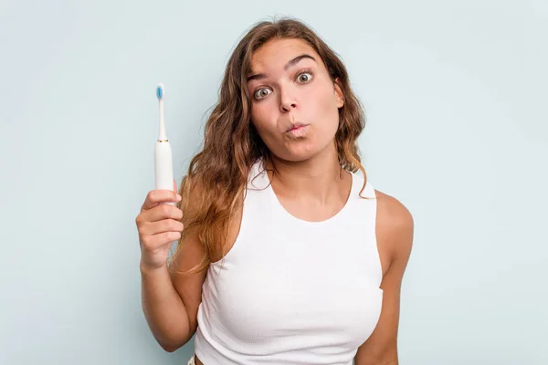 Junge Kaukasische Frau Mit Elektrischer Zahnbürste Isoliert Blauer Hintergrund Zuckt — Stockfoto