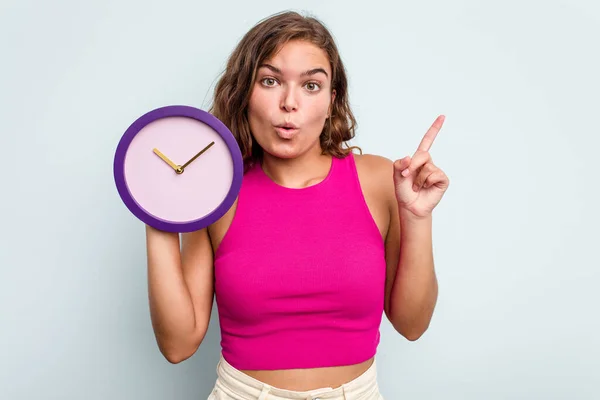 Joven Mujer Caucásica Sosteniendo Reloj Aislado Sobre Fondo Azul Que —  Fotos de Stock