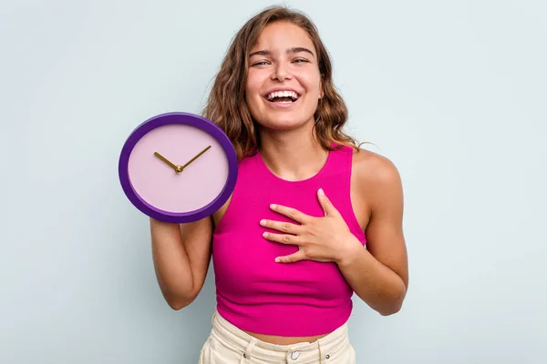 Joven Mujer Caucásica Sosteniendo Reloj Aislado Sobre Fondo Azul Ríe —  Fotos de Stock