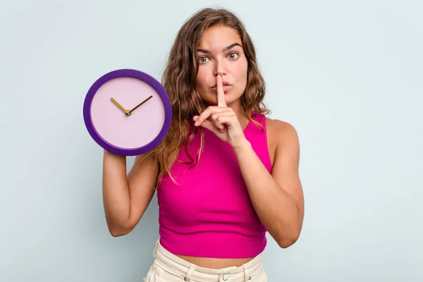 Mujer Caucásica Joven Sosteniendo Reloj Aislado Sobre Fondo Azul Manteniendo —  Fotos de Stock