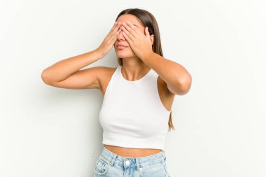 Beyaz arka planda izole edilmiş genç bir Hintli kadın elleriyle gözlerini kapatmaktan korkuyor..