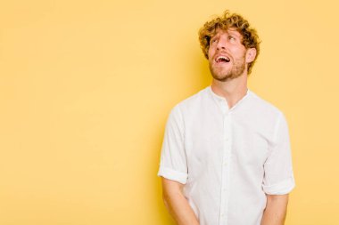 Sarı arka planda izole edilmiş genç beyaz bir adam çok kızgın, öfkeli, hayal kırıklığına uğramış diye bağırıyor..