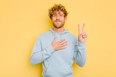 Sarı arka planda izole edilmiş genç beyaz adam yemin ediyor, elini göğsüne koyuyor..