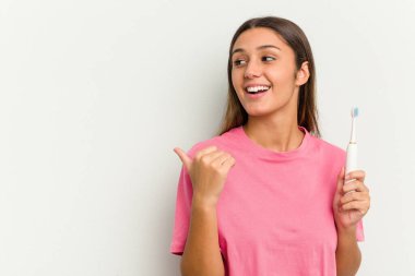 Beyaz arka plan noktalarında dişlerini fırçalayan genç Hintli kadın başparmak uzakta, gülüyor ve kaygısız..