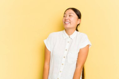 Sarı arka planda izole edilmiş genç bir Asyalı kadın. Rahatlamış ve mutlu bir şekilde gülüyor. Boynunda diş izleri var..