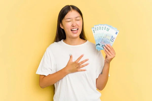 Young Asian Woman Holding Banknotes Isolated Yellow Background Laughs Out — Stock Photo, Image