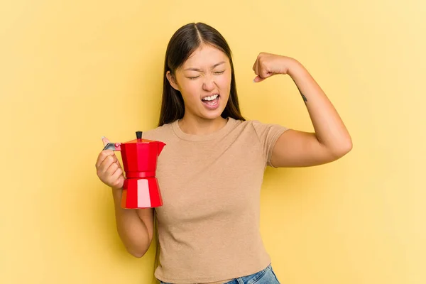 Junge Asiatin Hält Kaffeemaschine Isoliert Auf Gelbem Hintergrund Und Hebt — Stockfoto