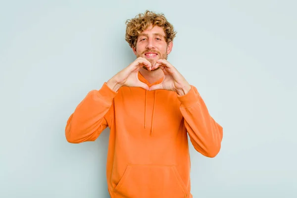 Jovem Caucasiano Isolado Fundo Azul Sorrindo Mostrando Uma Forma Coração — Fotografia de Stock