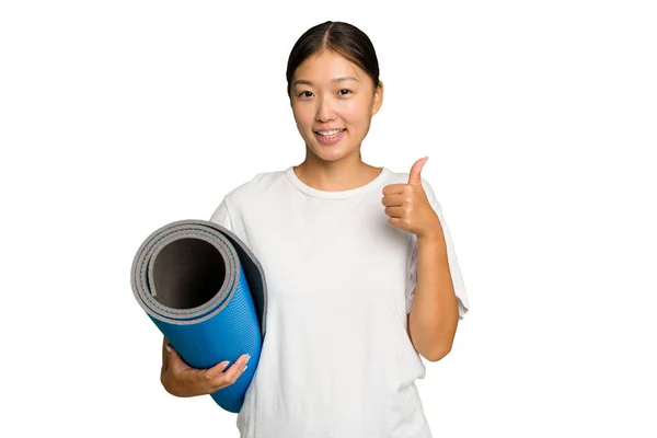年轻的亚洲女人拿着一个被绿色背景隔离的垫子 微笑着举起大拇指 — 图库照片