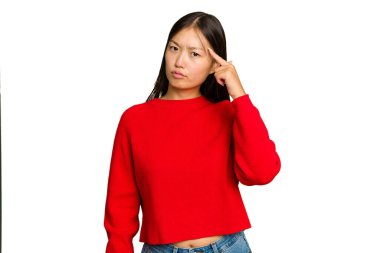 Genç Asyalı kadın yeşil renkli arka planda izole edilmiş. Şakağı işaret ediyor, düşünüyor, bir göreve odaklanıyor..