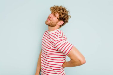 Mavi arka planda izole edilmiş beyaz bir adam sırt ağrısı çekiyor..